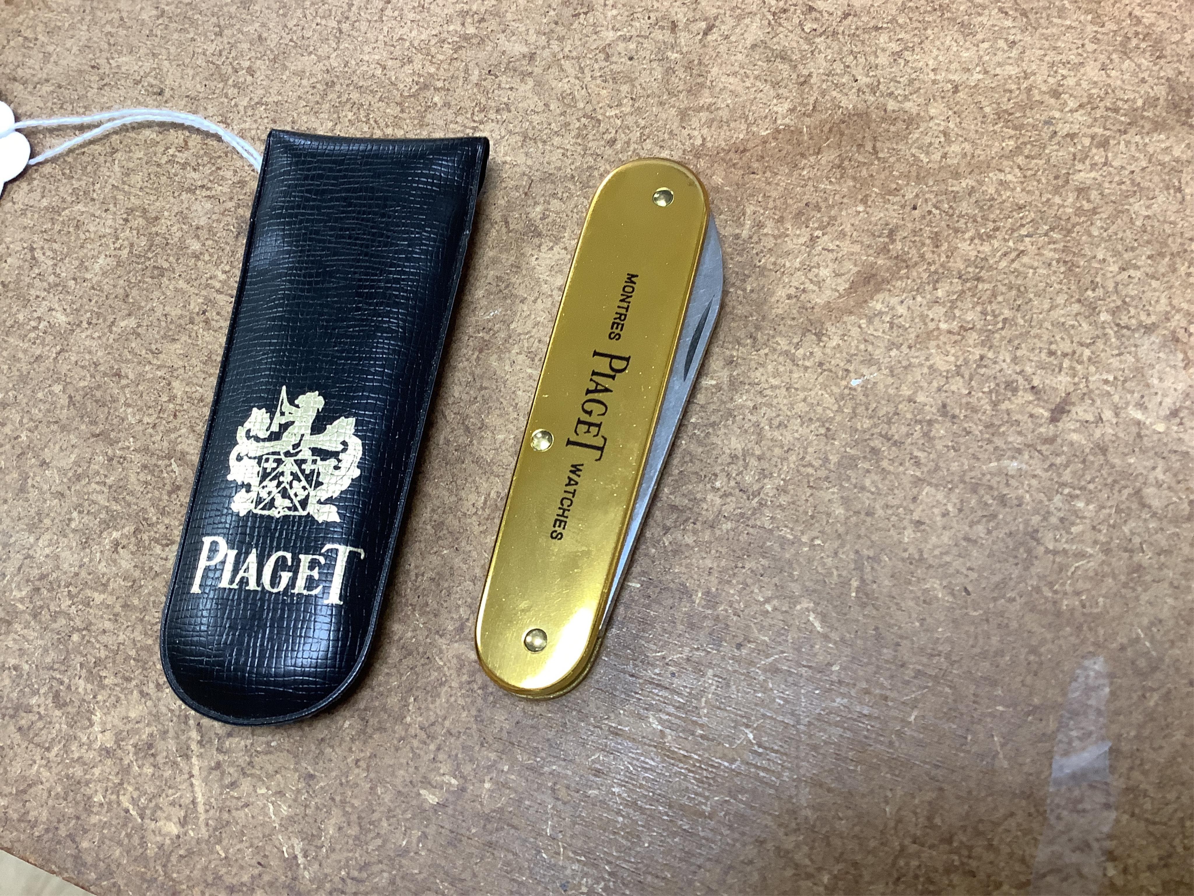 A Dupont gilt metal and blue enamel cigarette lighter with Japanese characters to the side, boxed with papers and a Piaget Montres Watches folding knife, cased. Condition - good